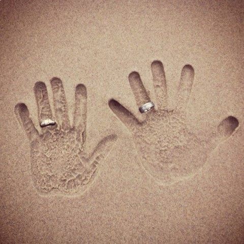 mãos na areia com as alianças